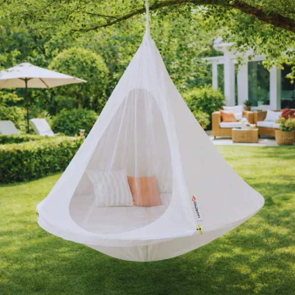 Tente suspendue hamac cocon écru avec moustiquaire installée dans jardin, espace détente extérieur