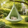 Tente suspendue hamac cocon vert avec coussins installée dans jardin, espace détente extérieur