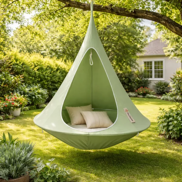 Tente suspendue hamac cocon vert avec coussins installée dans jardin, espace détente extérieur