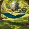 Hamac 1 place en coton bleu canard avec barres en bois suspendu entre arbres dans jardin