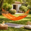 Hamac 1 place en coton orange avec barres en bois suspendu entre arbres dans jardin